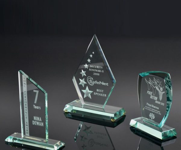 Three green glass awards with unique designs on them