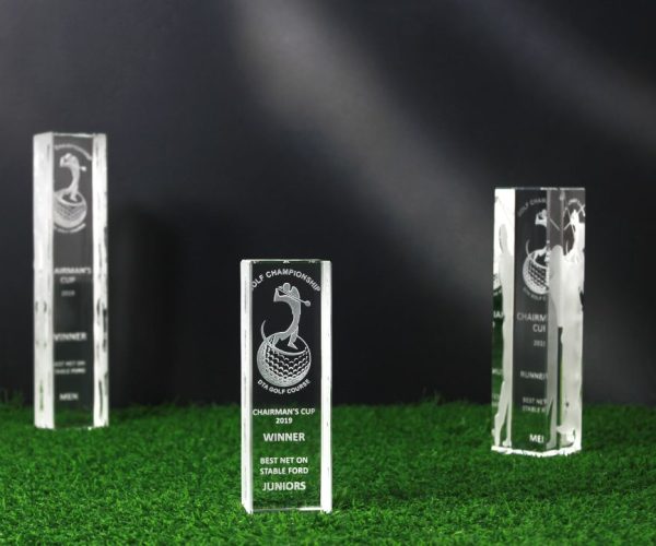 Three crystal golf trophy on grass.